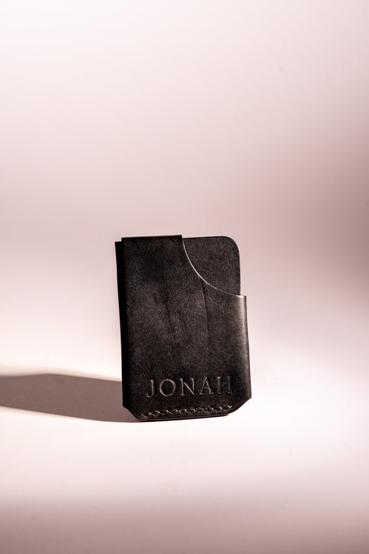 Black leather phone case with 'JONAH' branding on a light pink background